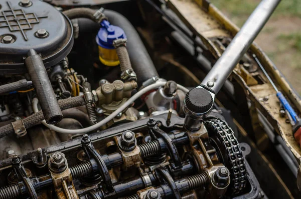 The procedure for tightening the cylinder head bolts. Part 5 of 6. Tightening the nut with a special torque wrench near the timing chain. Detailed shot of a carburetor engine without valve cover. Side view. Selective focus.