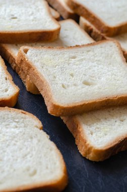 Sandviç ekmeği arka planı. Masanın üzerinde dikdörtgen ekmek yığını var. Açılı yan görüş. Yakın plan. Seçici odak.