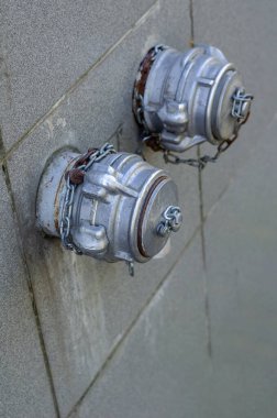 Duvarda alüminyum yangın muslukları ve zincirleri var. Binanın dışında iki yangın musluğu var. Yangın güvenliği.