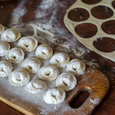 Kesme tahtasına porsiyon hamur köftesi heykeli. Mutfak masasında çiğ börek. Lezzetli ev yapımı yemekler pişirmek. Bir açıyla üstteki görünüm.