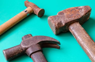 Turkuaz arka planda klasik çekiçler. Renkli arka planda üç eski paslı çekiç. El aletleri ve işçilik. Mesaj için yer. Bir açıdan üstten bak. Seçici odaklanma. Yakın plan..