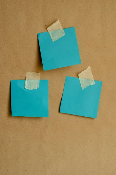 Colored paper for notes attached to the wall. Turquoise blank forms with adhesive tape on a plain wall. Front view. Training, business, media..