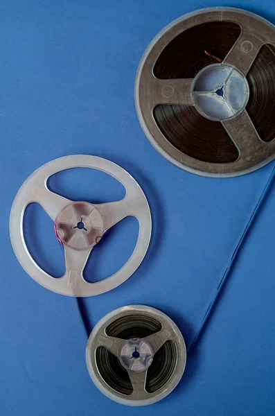 Three reels connected by audio tape. Composition of audio reels simulating the reproduction of an analogue music film. Old bobbins with dust and scratches.
