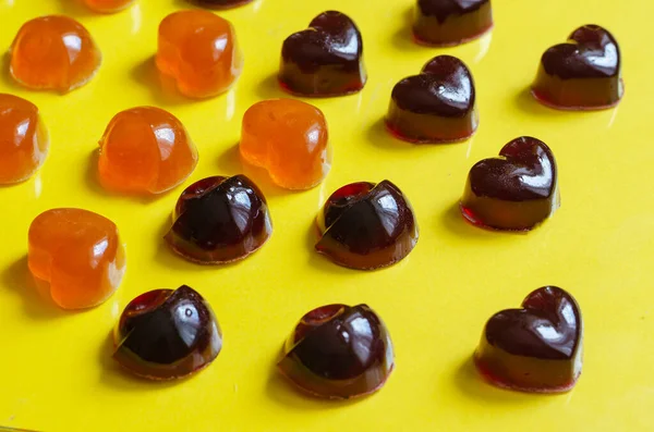 Homemade gelatin candies on a yellow background. Jelly candies with blackcurrant juice and apricot. Sweet sweets for children with natural colors. Treats without sugar. Close-up. Selective focus.