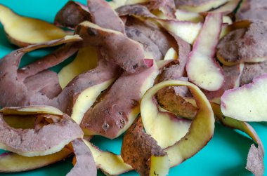 Patates soyuyordum. Masada patates olan bir yığın taze kabuk. Yemek pişirme süreci. Yiyecek atıkları. Seçici odak.