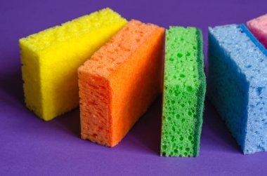 Mutfak süngeri eflatun arka planda. Çok renkli mutfak süngeri seti. Ev rutini ve ticari temizlik şirketi. Seçici odak.