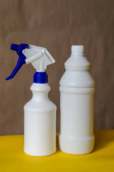 White plastic containers for household detergents on two-tone background.