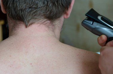 Saçları dökülmemiş bir adamın arkasından görünüşü. Sırtında kısa saçlı yetişkin bir adam. Saçları dağınık ve boynu kıllı yetişkin bir adam. Kendini soyutlama sırasında evde saç kesimi.