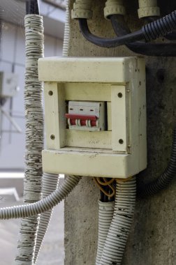 Dışarıdaki beton bir sütunun üzerinde eski bir üç direkli elektrik düğmesi. Açık hava aydınlatma düğmesi tozlu, çamurlu ve örümcek ağlı. Elektrik emniyeti. Seçici odak.