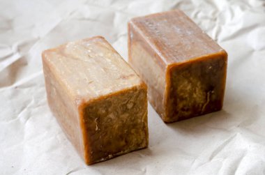 Doğal bir yakın plan dikdörtgen şeklinde büyük parçalar. Kahverengi kağıtta iki eko sabun. Doğal kişisel bakım ürünleri. Seçici odak.