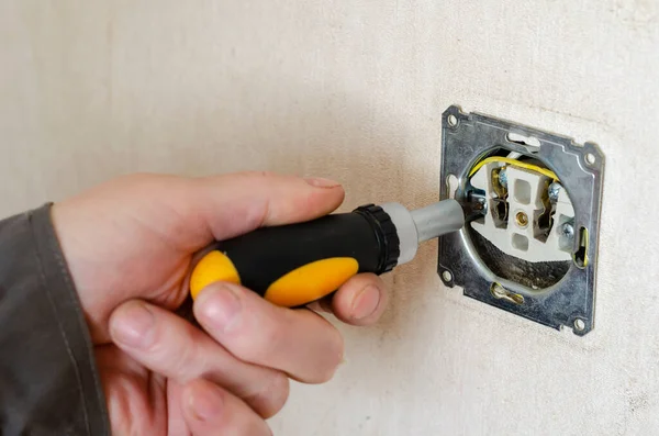 Repair of an electrical outlet part 5 5. Male hand with a screwdriver repairs an electrical outlet. Commercial services of a professional electrician. Selective focus.