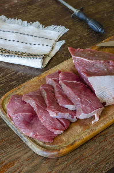 木板上的生牛肉片 一大块新鲜牛肉软骨素和五块薄薄的肉 准备肉食的过程 顶视图在一个角度 有选择的重点 — 图库照片