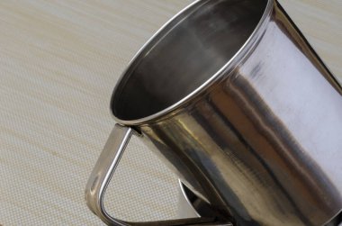 Arka planda paslanmaz çelik bardaklar var. Sıcak içecek ve yiyecek için bir çift kupa. Turizm, balık tutmak ve avlanmak için tabaklar. Bir açıdan üstten bak. Yakın plan. Seçici odak.