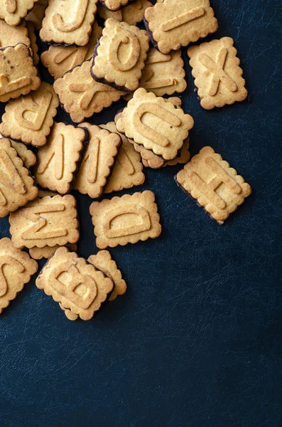 Cookies alphabet close-up. A pile of biscuits with English letters background. Rectangular tasty cookies with a chocolate base. Creative multitask background. Flat lay