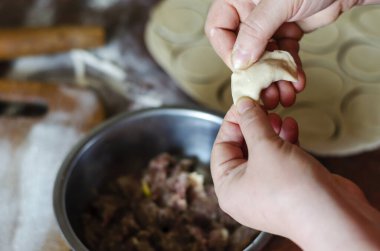 Kadın elleri mutfak masasında etli hamur köfteleri yontuyor. Bir dilim kıyma ve hamur dilimi ile yetişkin bir kadının ellerine yakın çekim. Ev yapımı etli börek yapma süreci. Ev yapımı yemek..
