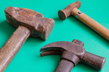 Turkuaz arka planda paslı çekiçler. Farklı boyutlarda üç klasik çekiç. El işi, el işi. Yan görüş. Yakın plan. Seçici odak.