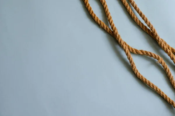 浅蓝色背景上的细黄麻绳 天然的绳子被随意地放在桌子上 海上旅行 海滨度假 设计任务的多任务背景 案文的位置 — 图库照片
