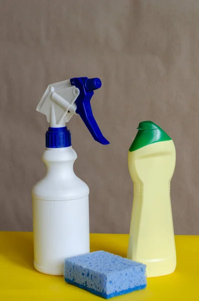 Plastic bottles with cleaning products and sponge on a two-color background. Various containers for household chemicals. Cleaning companies or products. Side view. Close-up.