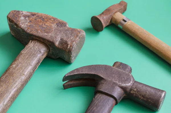 Old rusty hammers on a turquoise background. Three random vintage hammers of different sizes. Craft, manual labor. Side view. Close-up. Selective focus.