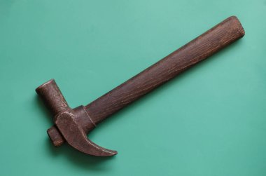 Turkuaz arka planda paslı eski bir çekiç. Sıkıştırılmış ahşap saplı tek çekiç. El işi, el işi. Yukarıdan bak. Yakın plan..