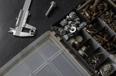 Siyah arka planda cıvatalı ve daha kalibreli bir organizatör. Çeşitli cıvatalarla plastik kutuyu aç. Çapı ve boyutu için uygun seçimler. Yukarıdan görüntüle.