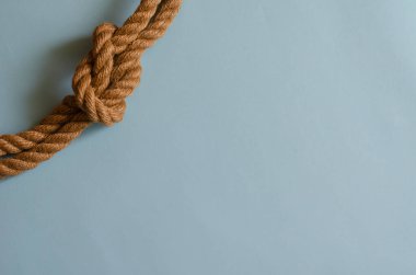 Açık mavi arka planda deniz düğümlü kenevir otu ipi. Düğümlenmiş doğal ip. Tasarım görevleri için çoklu görev arkaplanı. Metin için yer.