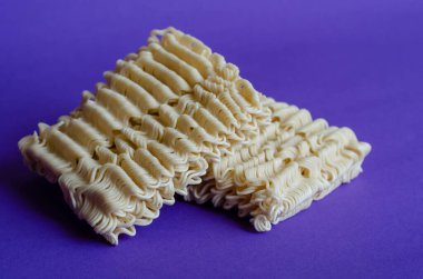 Mavi arka planda kuru erişte dikdörtgenleri. Paketsiz iki porsiyon hazır şehriye. Fast food sağlıksız. Yakın plan. Seçici odak.