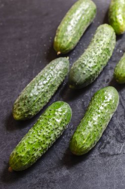 Bahçeden taze sebze topladım. Karanlık bir masada taze kokulu salatalıklar. Yeni mahsul mevsimi. Kendi kendini yetiştirmiş sebzeler. Yakın plan. Seçici odak.