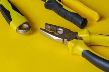 Sarı arka planda siyah ve sarı saplı el aletleri. Metal için makas, ayarlanabilir anahtar ve kerpeten masanın üzerinde. Yüksek kalite profesyonel alet. Mesaj için yer. Yan görüş. Seçici odak.