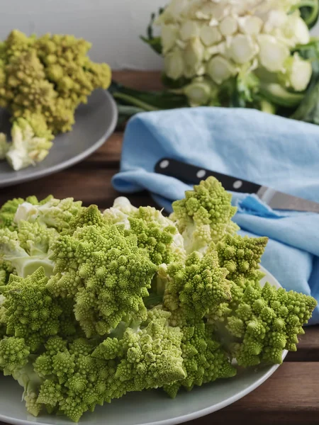 Sliced roman cauliflower in plates on a wooden table. Close-up. Healthy eating concept — Stock Fotó