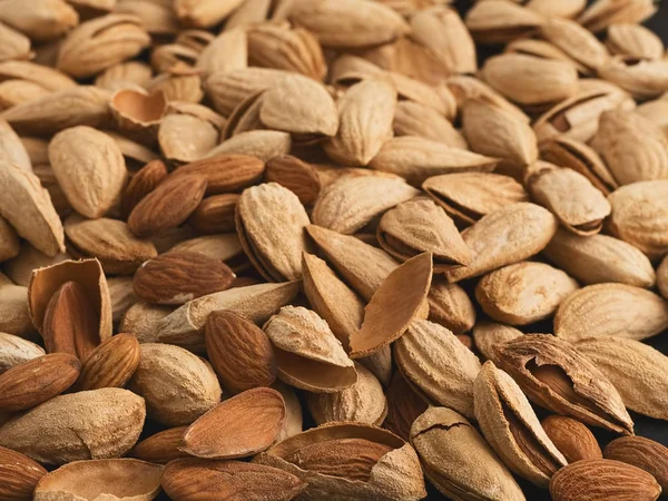 Raw natural organic almonds scattered on the background. Close-up. Healthy eating concept. Natural light. Selective focus