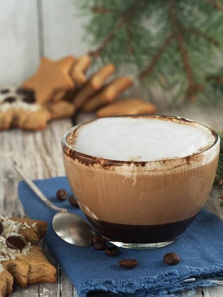 Galletas de jengibre caseras de Navidad, y una taza de vidrio con café capuchino caliente. Primer plano. Fondo vintage de madera, cerca de las ramas de abeto . — Foto de Stock