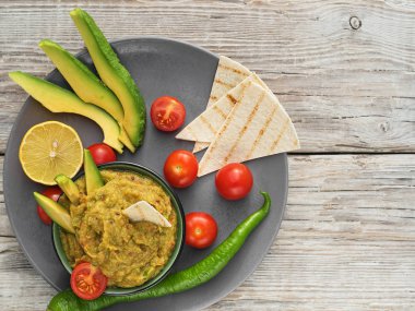 Geleneksel Latince, Meksika guacamole soslu killi kase. Ev yapımı guacamole için malzemeler: avokado, limon, tuz, biber, domates ve tartilla. en üstteki görünüm.