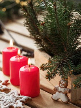 Ev yapımı lezzetli zencefilli kurabiyeler üç yanan mum, ahşap arka plan. Yakın plan. Noel ağacı dalları.