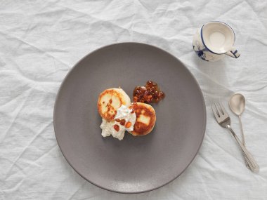 Kremalı peynirli kek ya da beyaz masa örtüsü üzerinde gri bir tabakta deniz dikenli reçel. Vintage sos kabı. Ev yapımı peynirli börek. Lezzetli bir kahvaltı. Üst görünüm.