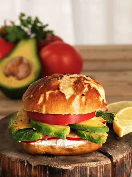 Vegetarian burger with avacado, radish, soft cheese and tomato on a plate. Homemade bun with seeds. Ingredients for a burger. Vertical orientation. Close-up.