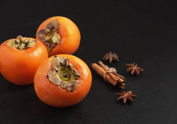 Lahodné čerstvé plody persimmon na černém pozadí. Detailní záběr. Složky a koření pro persimmon džem. — Stock fotografie