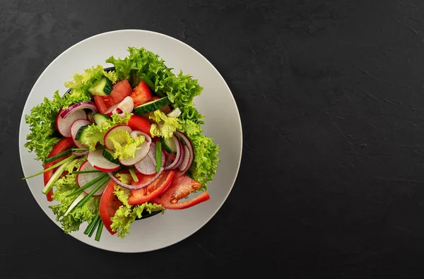 Gri bir tabakta siyah bir fincanda taze sebze salatası. Yukarıdan bak. Uzayı kopyala Siyah arkaplan.