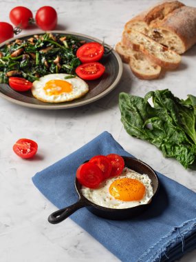 Gri bir masanın üzerinde kızarmış ıspanak ve mantarlı leziz kızarmış yumurta. Yakın plan. Dikey yönelim.