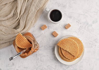 Işık masasında cam bir kavanozda ev yapımı karamel sosu. Beyaz bardakta espresso ve taze waffle. Üst manzara Tatlı tatlı tatlı.