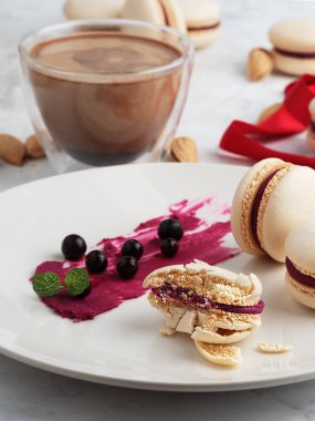 Gri bir tabakta üzümlü ev yapımı badem kurabiyesi. Frenk üzümü, nane yaprakları ve bir tabakta bisküvi. Yakın plan. Hediye paketi için kırmızı kurdele ve arka planda bir fincan kahve..