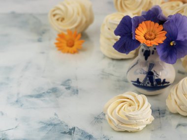 Gri bir masada ev yapımı kayısı şekerlemeleri. Vazoda bahar çiçekleri, marşmelovların yanında. Yakın çekim, yatay yönlendirme. Zephyr 'e odaklan. Boşluğu kopyala.