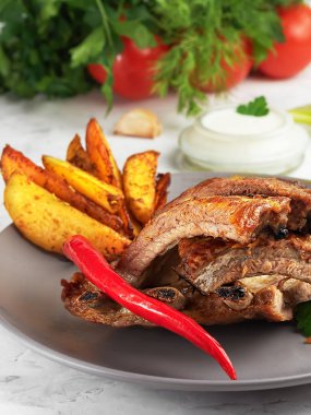 Izgara kaburga, Idaho patatesi ve sebzeli, gri arka planda. Yüzeyin derinliği. Dikey yönelim, yakın plan.