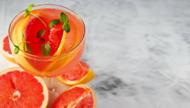 Alkol ve buz küplü soğuk greyfurt suyu, gri arka planda bir dilim greyfurt ve nane şekeri ile süslenmiş. Uzayı kopyala Üst görünüm, seçici odaklanma. Greyfurt dilimlerinin yanında..