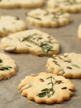 Yakın plan. Kokulu otlarla, tohumlarla ve parmesanlı taze kurabiyeler. Kraker yapma süreci. Ev yemeği kavramı.