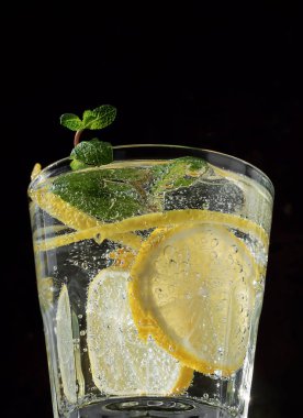 Siyah arka planda soğuk bir içecek. Bir bardak limonata ya da naneli mojito kokteyli. Kapat.