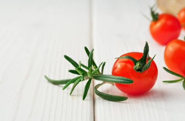 Taze olgun domatesler ve beyaz ahşap yüzeydeki biberiye dalıyla doğal ışık, yakın çekim, yazı için boşluk kopyalama. Organik yiyecekler