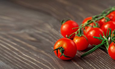 Koyu kırsal ahşap yüzeyde taze kiraz domatesleri ve biberiye dalıyla doğal ışık, yakın plan, metin için boşluk kopyala.