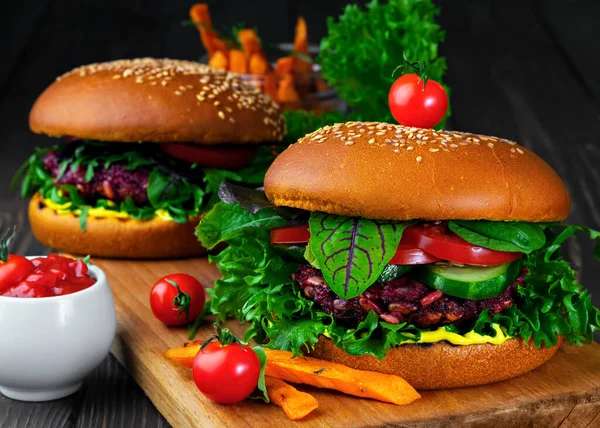 Pancar pirzolası, taze sebze, ızgara havuç, domates ve köri soslu taze vegan burger. Vejetaryen burger pişirmek için gerekli malzemeler. Bitkiler, baharatlar siyah ahşap arka planda. Kapat..