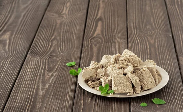 Koyu ahşap bir masada nane yapraklarıyla süslenmiş ayçiçeği halkası ile kaplanmış, seçici bir odak noktası. Boşluğu kopyala.
